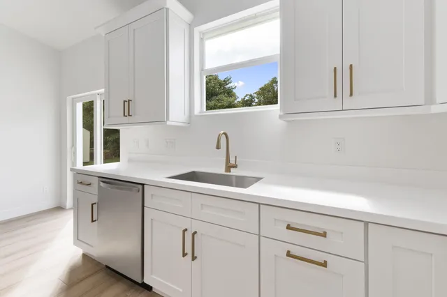 a kitchen with white cabinets and sink