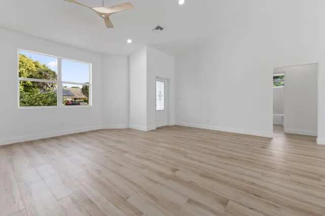 an empty room with wooden floor and windows