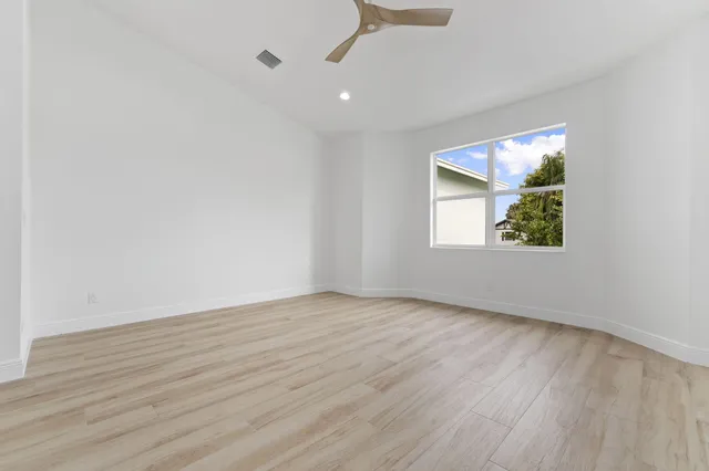 an empty room with wooden floor cabinet and windows