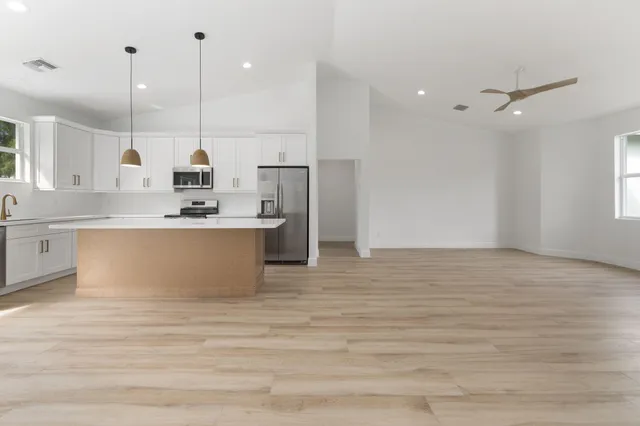 a large kitchen with stainless steel appliances kitchen island a large counter top and a wooden floors