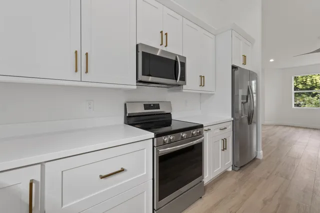 a kitchen with stainless steel appliances white cabinets and a stove a refrigerator with wooden floor