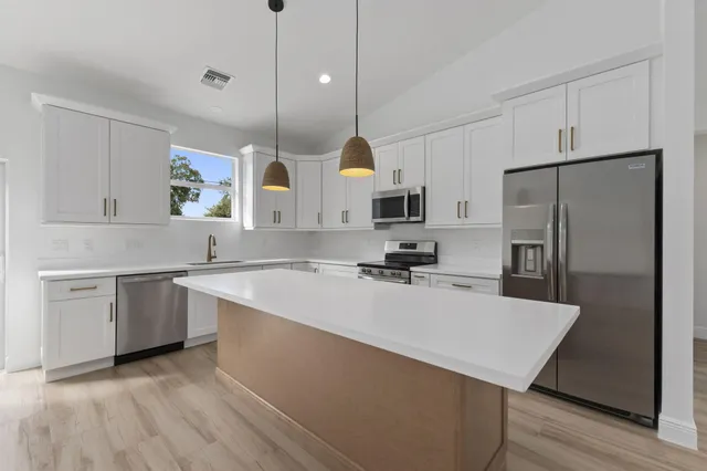 a kitchen with a sink a kitchen island a stove a microwave and island