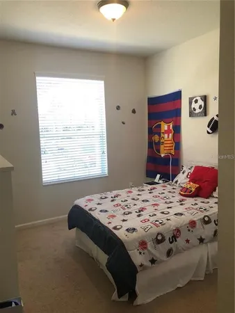 a bedroom with a bed and a dresser next to a window