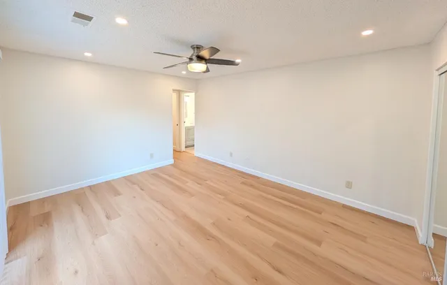 an empty room with a ceiling fan and wooden floor