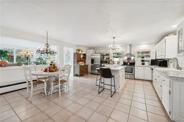 a kitchen with stainless steel appliances kitchen island granite countertop a dining table chairs and a white refrigerator