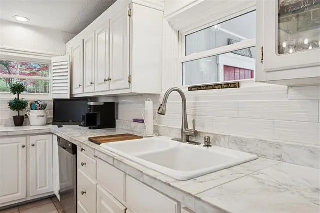a kitchen with stainless steel appliances granite countertop a sink a stove and white cabinets with wooden floor