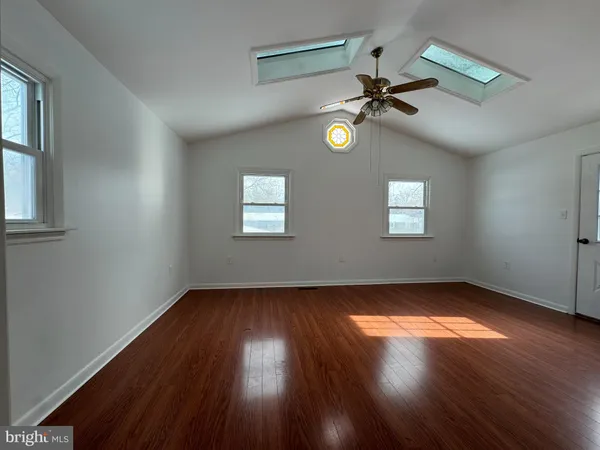an empty room with wooden floor fan and windows