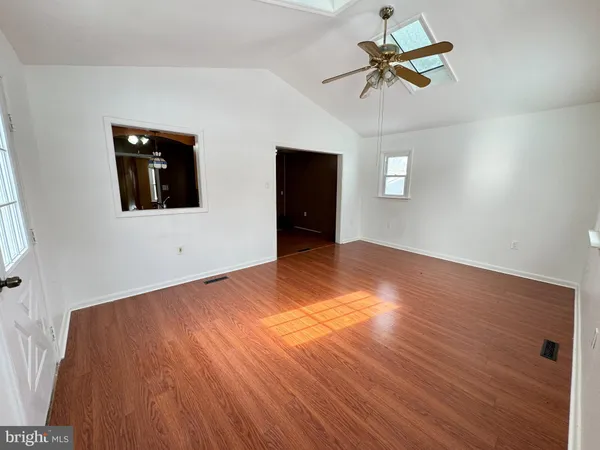 a view of a big room with wooden floor and windows
