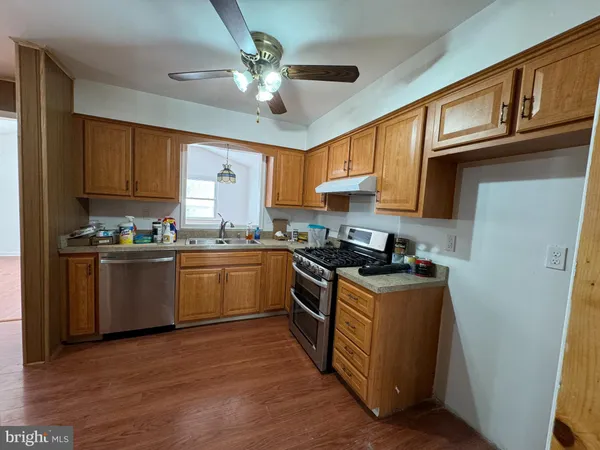 a kitchen with stainless steel appliances granite countertop a stove a sink dishwasher and a refrigerator with wooden floor
