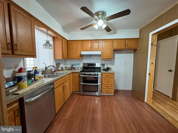 a kitchen with a chandelier a sink stainless steel appliances and cabinets