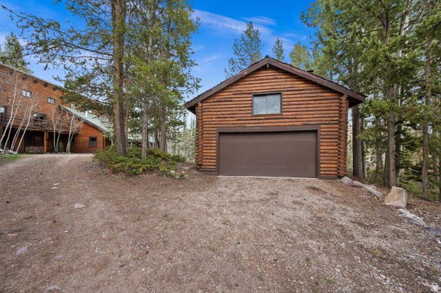 4725 Pine Ridge Road Evanston, UT 82930 - Photo 63 of 82 Detached log-style garage featuring a brown overhead door, a single upper window, and a gabled roofline