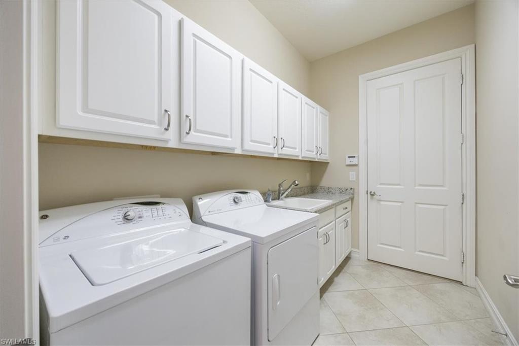 6504 Costa Circle Naples, FL 34113 - Photo 21 of 25 Clothes washing area with a sink, light tile patterned flooring, independent washer and dryer, baseboards, and cabinet space