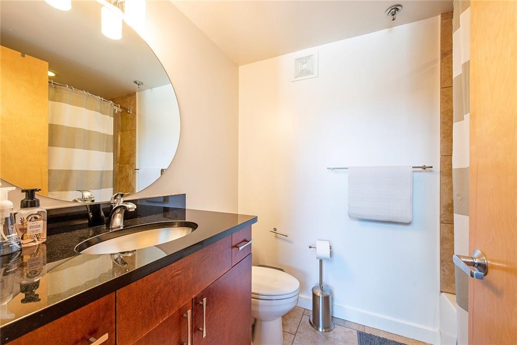 1661 La France Street Northeast, Unit 325 Atlanta, GA 30307 - Photo 32 of 40 a bathroom with a granite countertop sink toilet and mirror