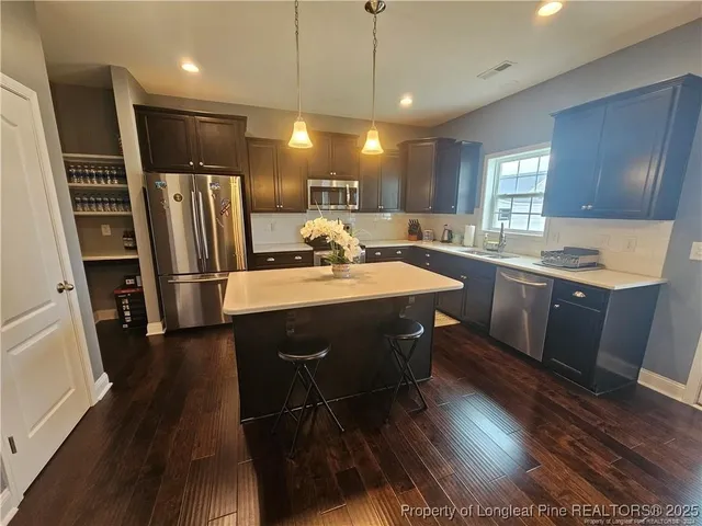 a kitchen with stainless steel appliances granite countertop a sink refrigerator and cabinets