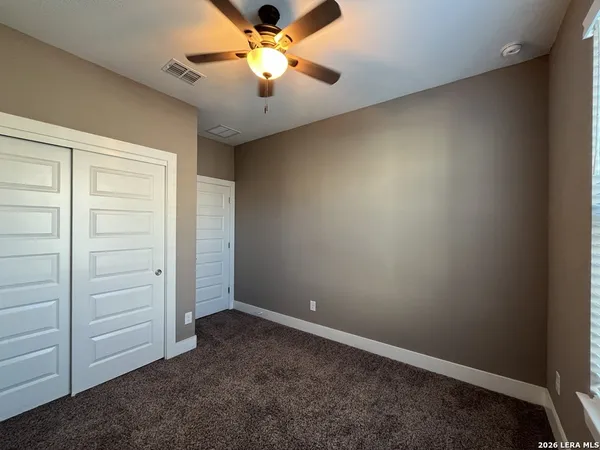 an empty room with closet and a ceiling fan