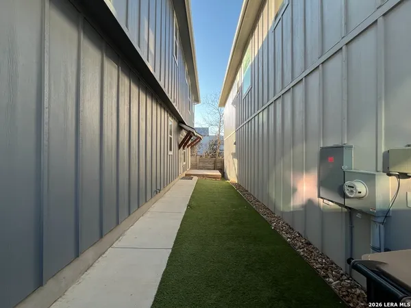 a view of a pathway of a house with backyard and wooden fence