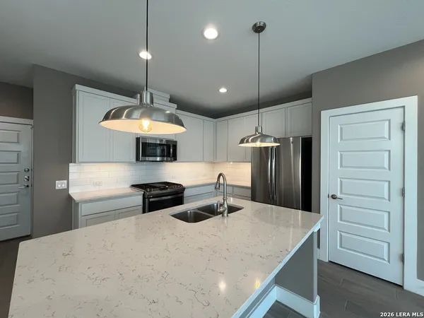 a kitchen with stainless steel appliances granite countertop a sink refrigerator and cabinets