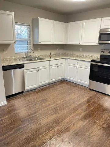 a white kitchen with granite countertop white cabinets and white appliances