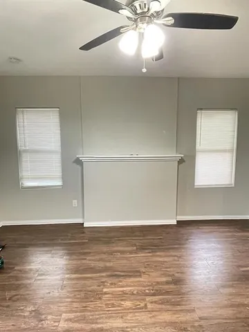 an empty room with wooden floor closet and windows