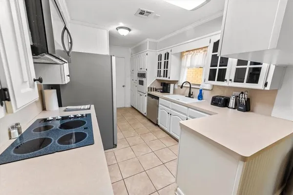 a kitchen with a sink a stove and white cabinets