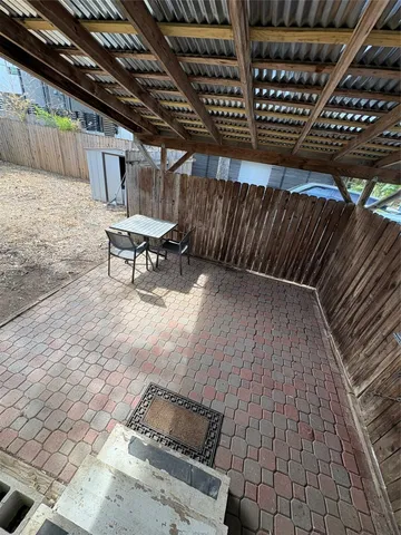 a view of a backyard with wooden fence and a large tree