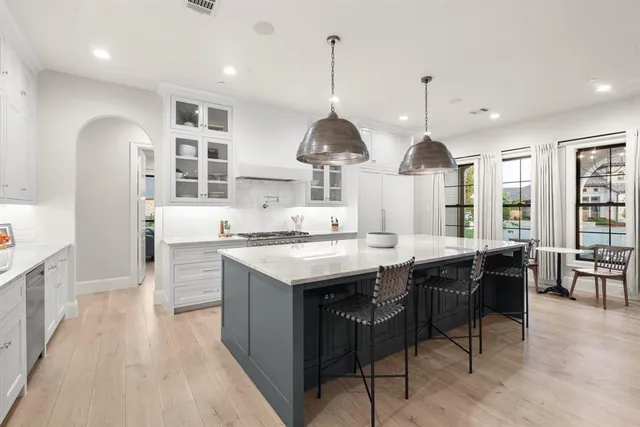 a kitchen with stainless steel appliances kitchen island granite countertop a sink a stove and a wooden floors