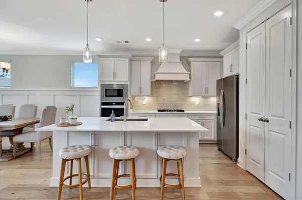a kitchen with stainless steel appliances a table chairs refrigerator and microwave