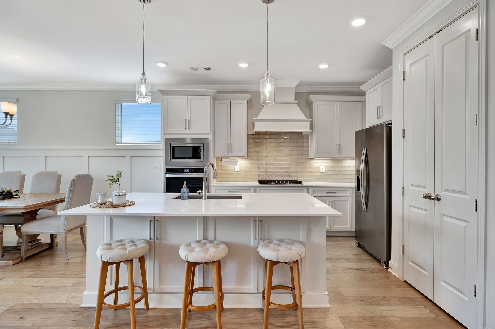a kitchen with stainless steel appliances a table chairs refrigerator and microwave