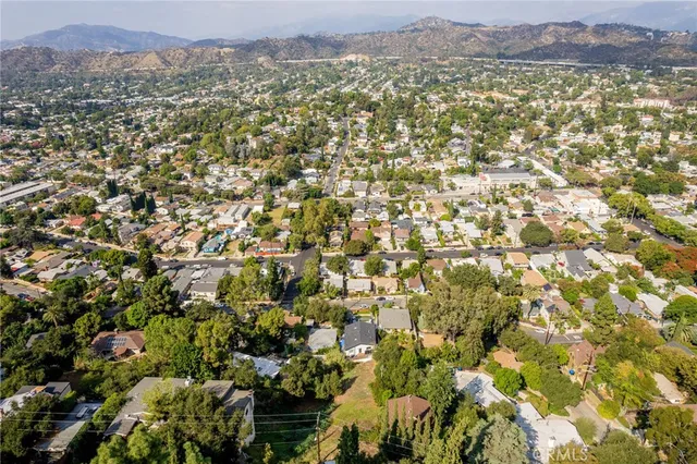 an aerial view of residential houses with outdoor space and trees