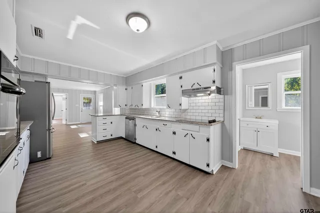 a view of a kitchen with stainless steel appliances a lot of counter space and wooden floor