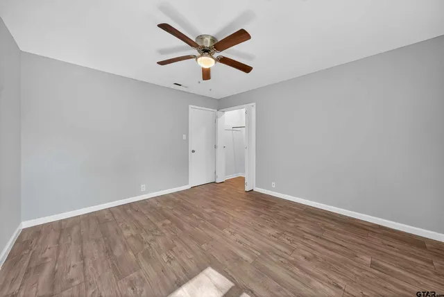 an empty room with wooden floor and ceiling fan
