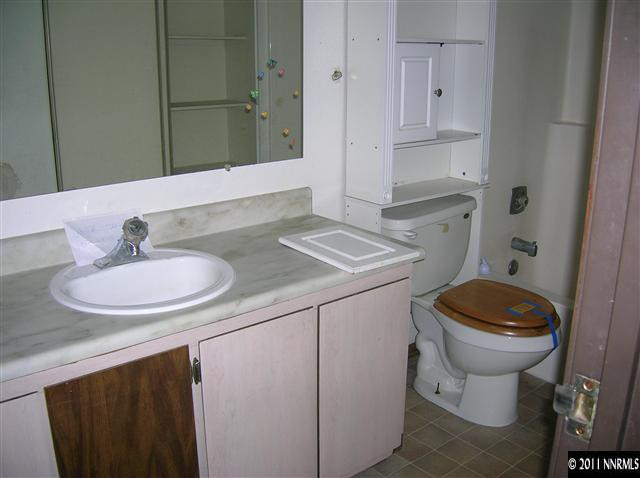 4602 Neil Road, Unit 90 Reno, NV 89502 - Photo 7 of 10 a bathroom with a granite countertop toilet sink and mirror
