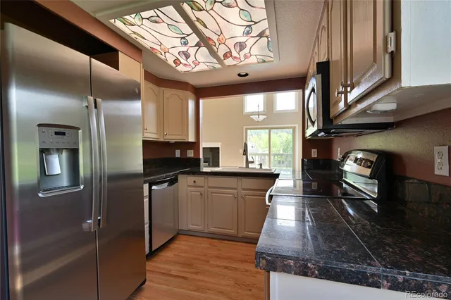 a kitchen with stainless steel appliances granite countertop a refrigerator a stove and a wooden floors