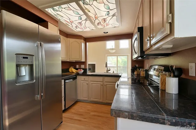 a kitchen with stainless steel appliances granite countertop a refrigerator a stove and a wooden floors
