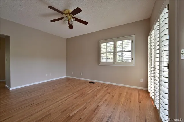 a view of an empty room with window and wooden floor