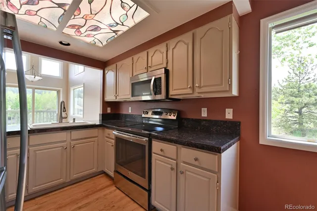 a kitchen with stainless steel appliances granite countertop a sink and cabinets with wooden floor