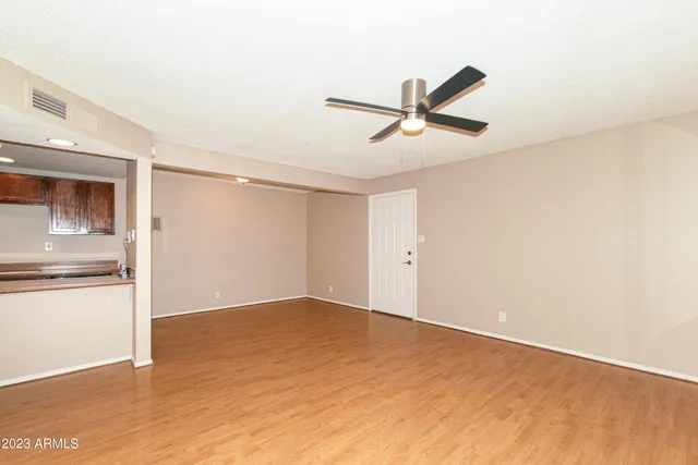 a view of a big room with wooden floor and a kitchen space