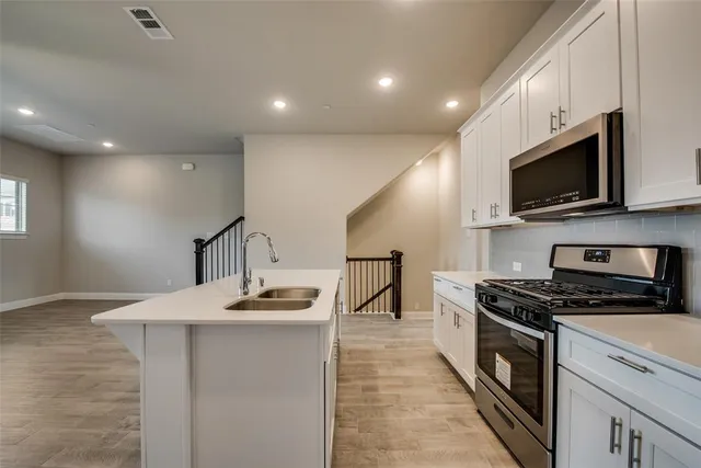 a kitchen with kitchen island granite countertop a sink stainless steel appliances and cabinets