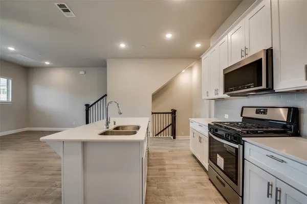 a kitchen with kitchen island granite countertop a sink stainless steel appliances and cabinets
