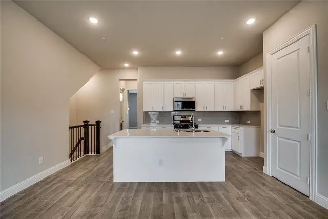 a large kitchen with stainless steel appliances a large counter top a stove and a refrigerator