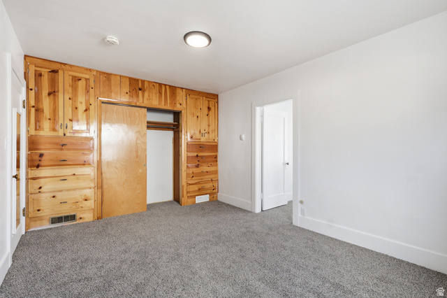 871 North 700 East Logan, UT 84321 - Photo 11 of 20 Unfurnished bedroom featuring carpet floors, a closet, and wooden walls