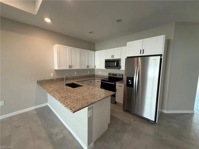 a kitchen with stainless steel appliances granite countertop a refrigerator a sink a stove a microwave and island