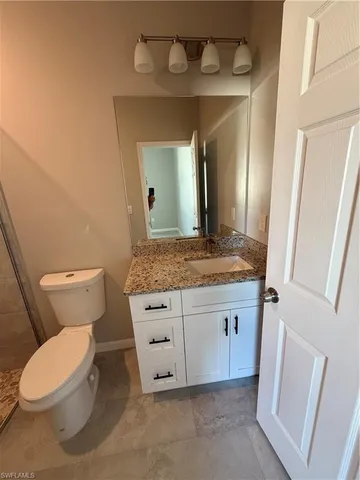 a bathroom with a granite countertop toilet sink and a mirror