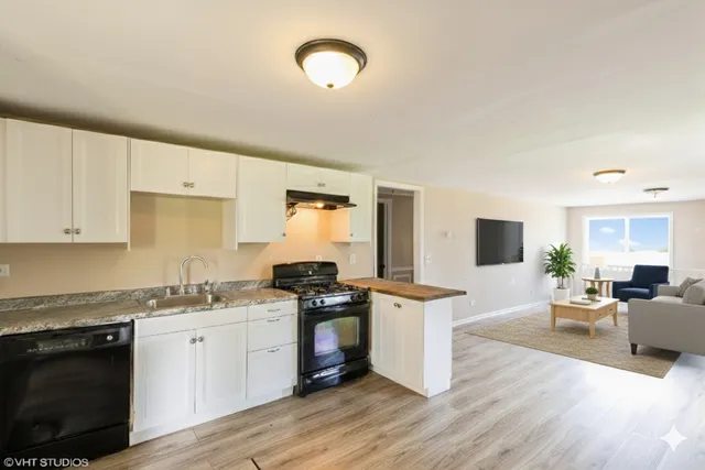 a kitchen with granite countertop a stove top oven a sink dishwasher and white cabinets with wooden floor