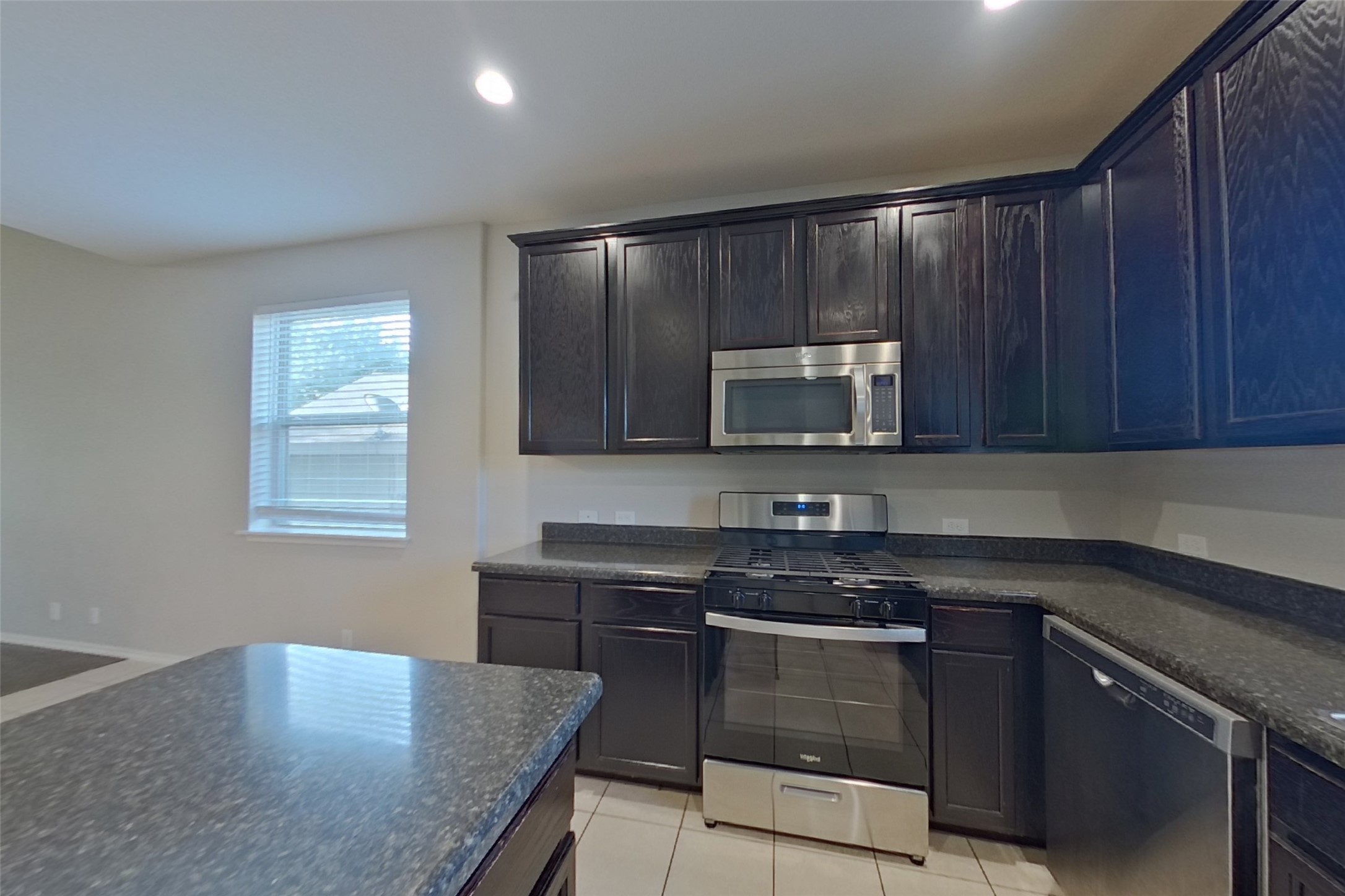 240 Dragon Ridge Road Buda, TX 78610 - Photo 6 of 20 Dark wood cabinetry pairs with stone countertops in this functional kitchen featuring a central island.