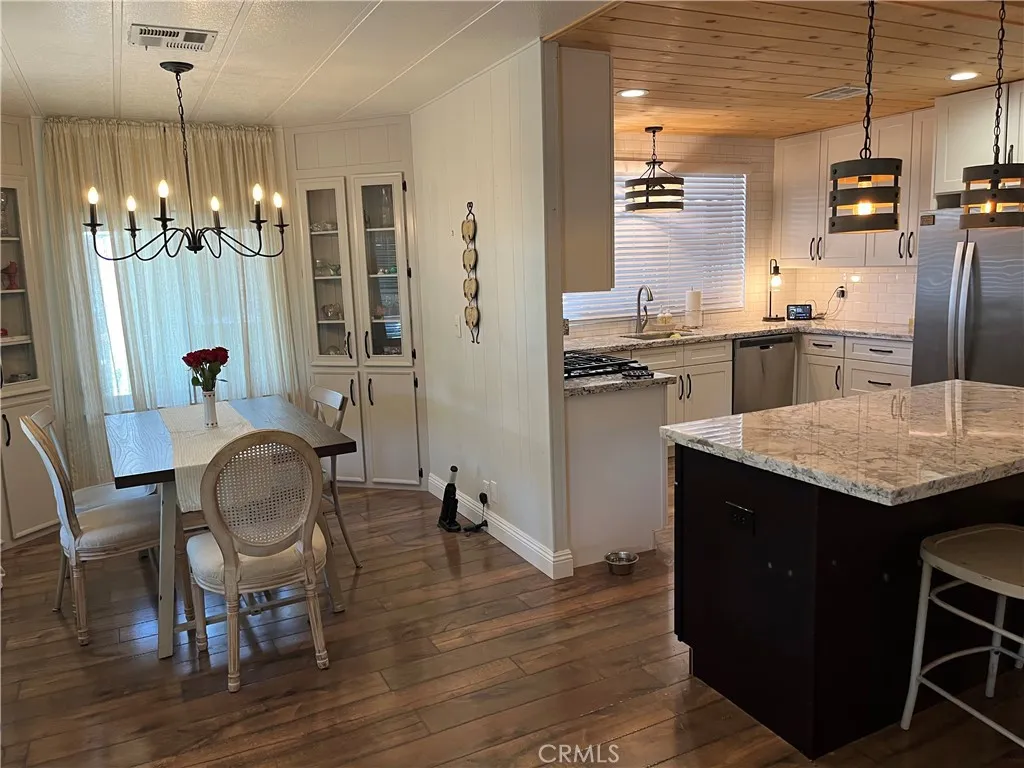 4000 Pierce Street, Unit 284 Riverside, CA 92503 - Photo 12 of 32 a kitchen with granite countertop kitchen island stainless steel appliances a table chairs sink and refrigerator