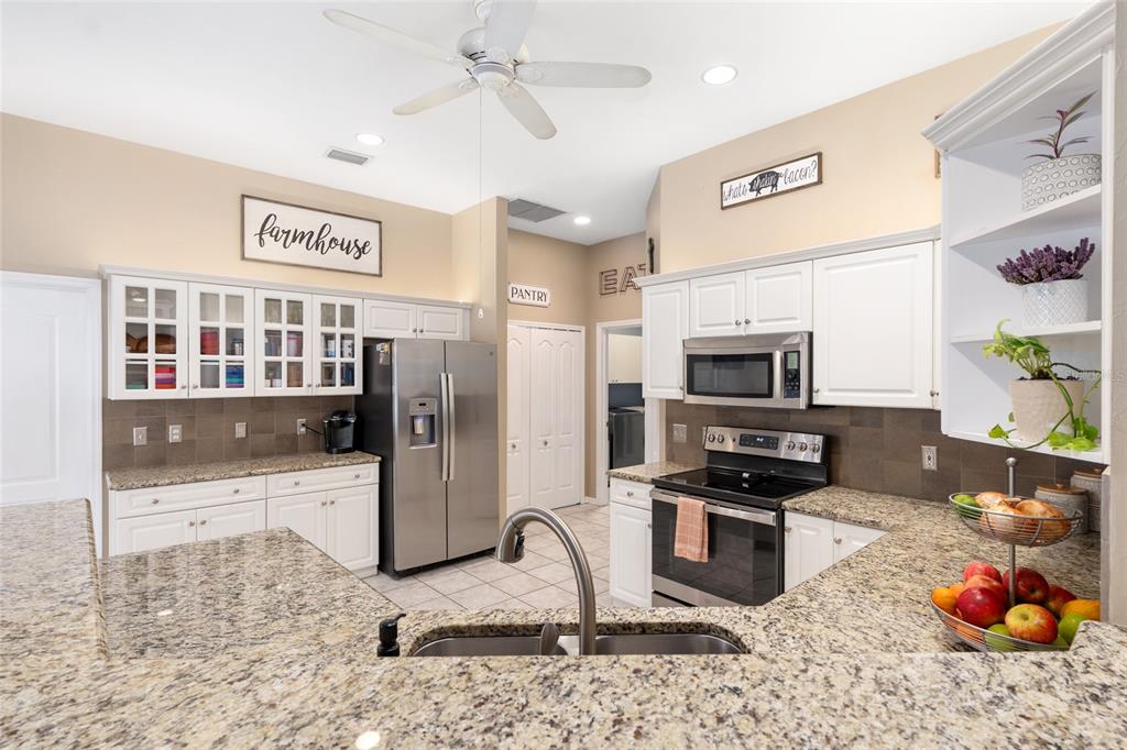 9350 Southwest 46 Place Gainesville, FL 32608 - Photo 23 of 63 a kitchen with stainless steel appliances kitchen island granite countertop a refrigerator stove and sink