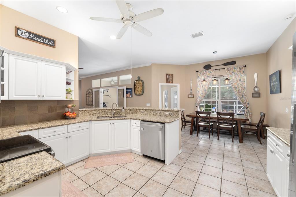 9350 Southwest 46 Place Gainesville, FL 32608 - Photo 26 of 63 a kitchen with granite countertop lots of white cabinets a sink a stove a dining table and chairs
