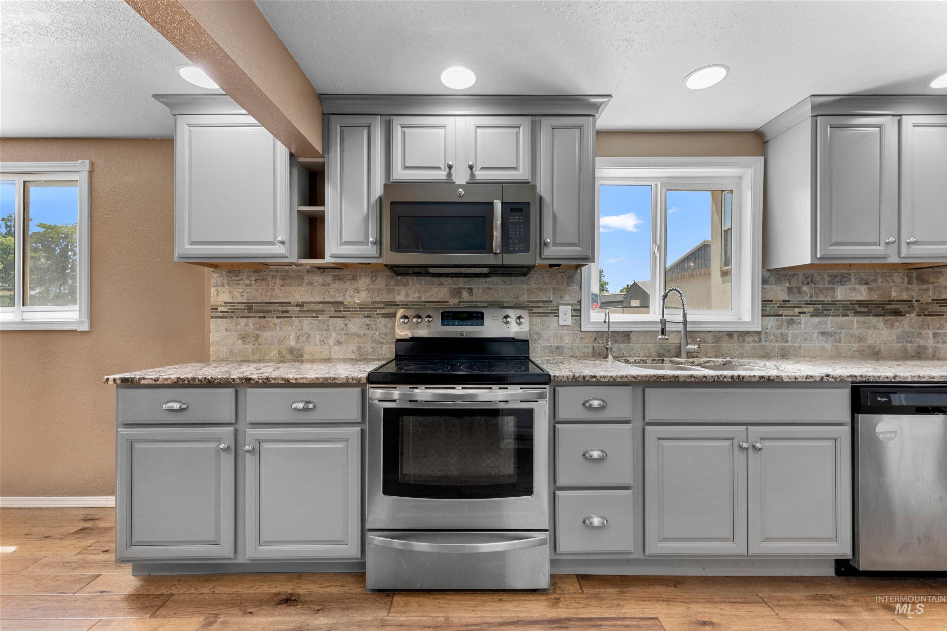17441 Upper Pleasant Ridge Road Caldwell, ID 83607 - Photo 11 of 40 Modern kitchen featuring wood-finish flooring, light gray cabinetry, and stone-look countertops
