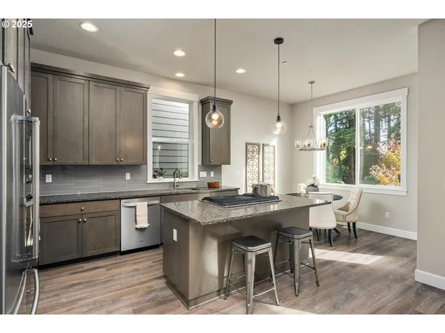 a kitchen with stainless steel appliances granite countertop a sink a stove a dining table and chairs